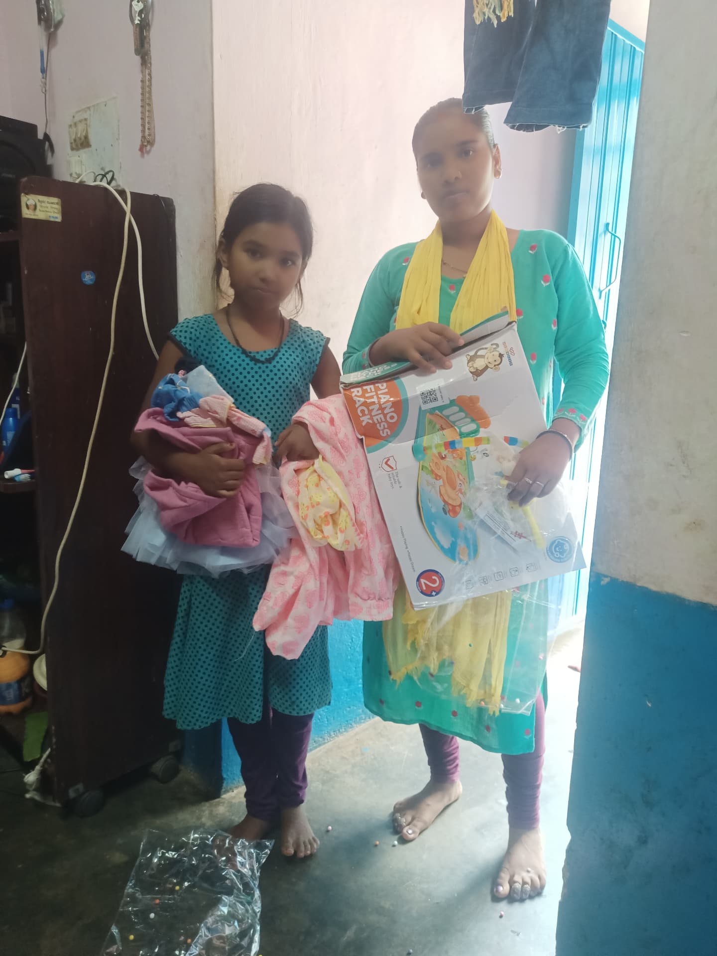 A mother and daughter receiving donated clothes and a toy