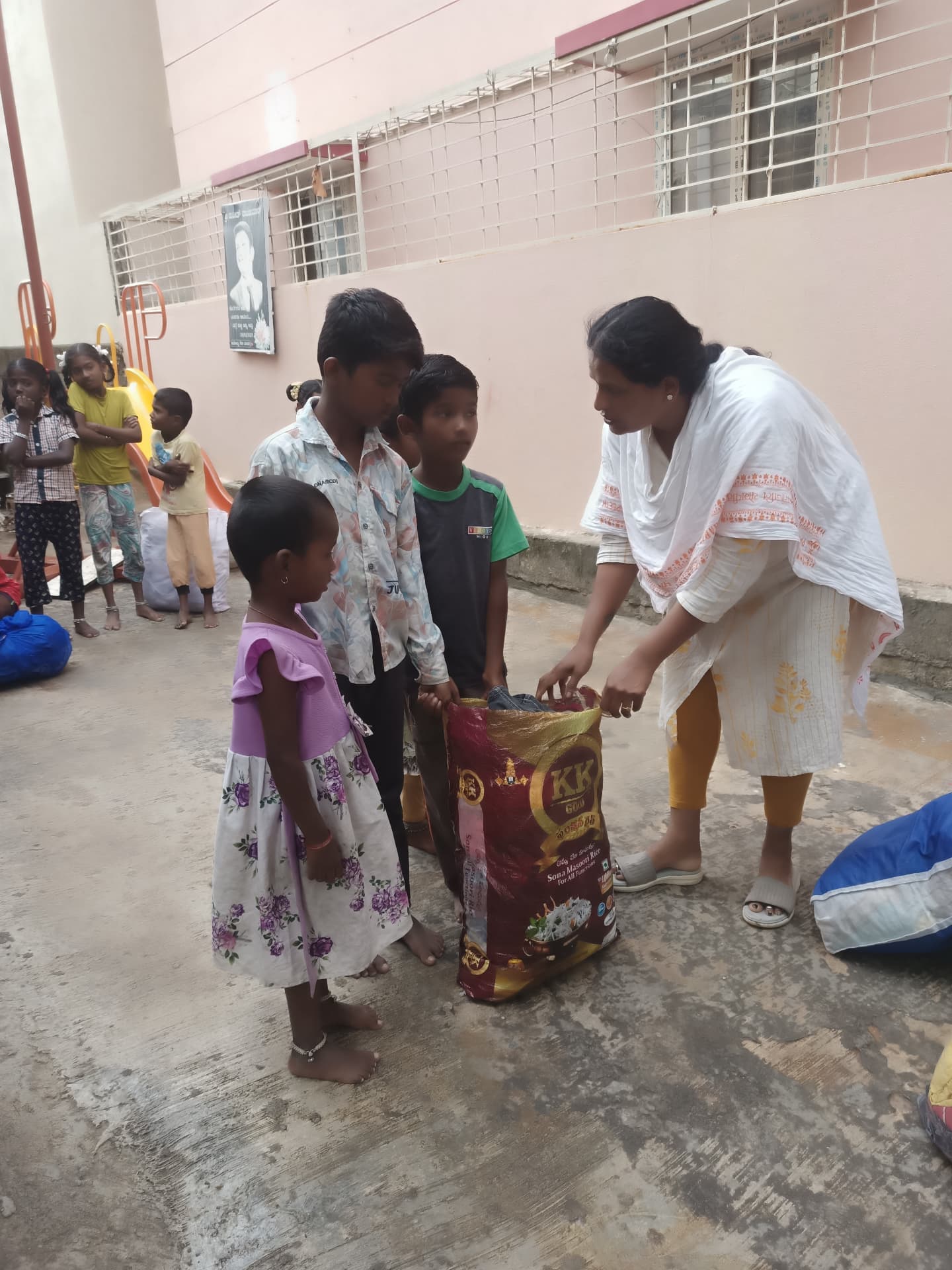 Volunteer distributing a sack of rice to children at a care home