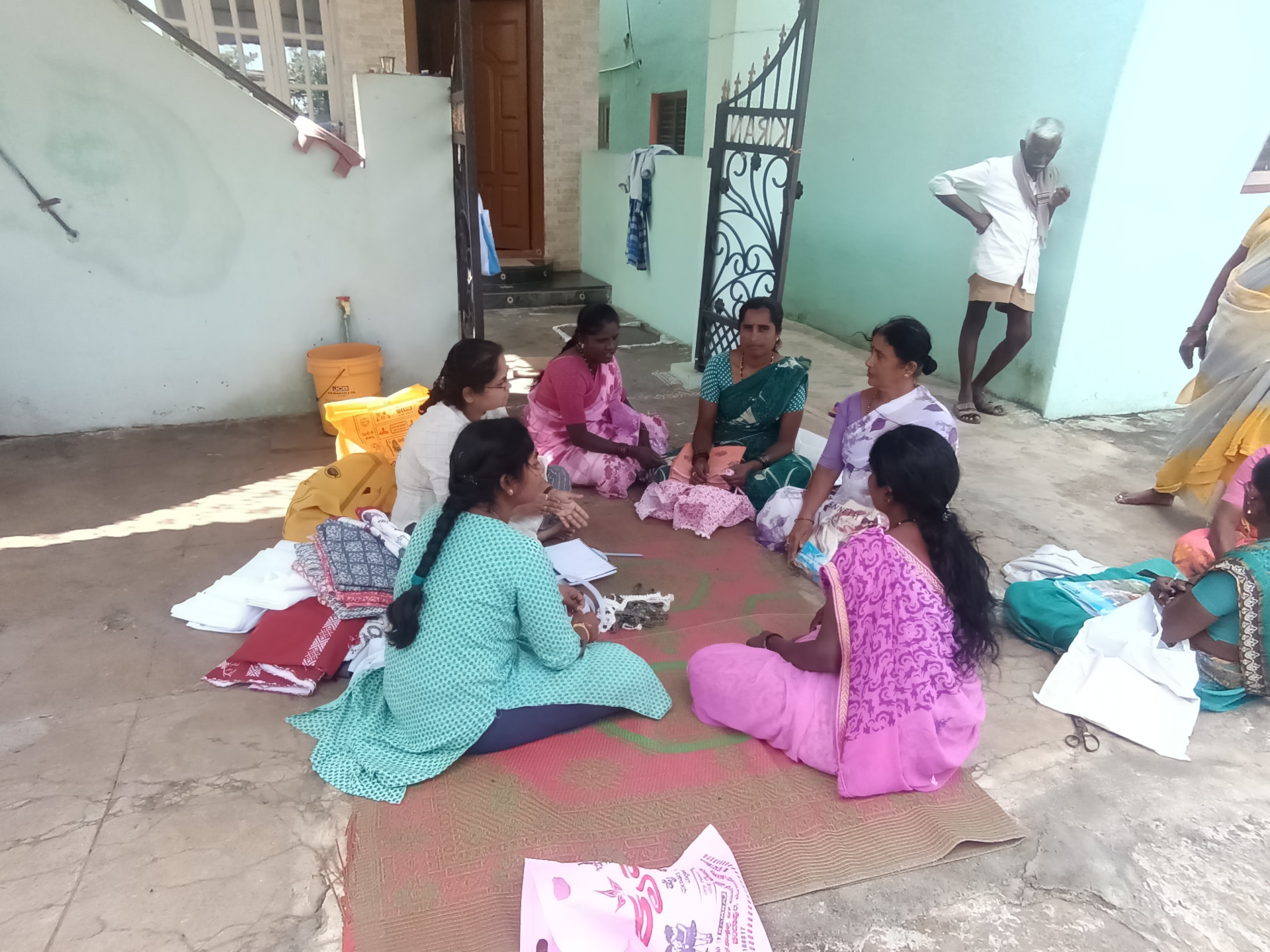 Women learning practical tailoring skills together in a community workshop